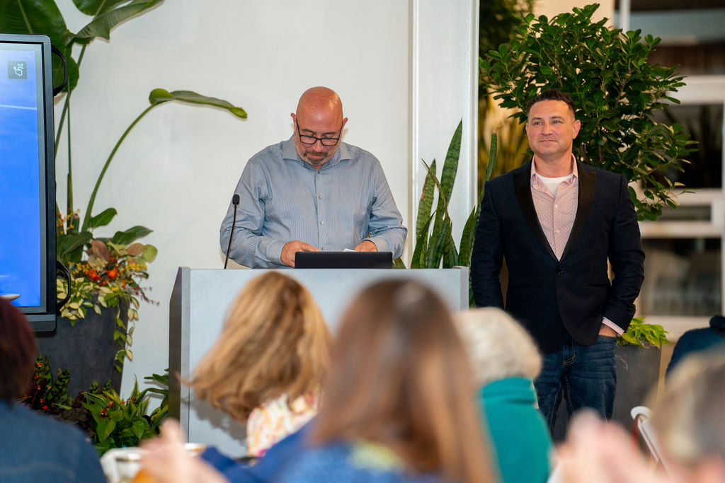 Two men standing at a podium in front of people.