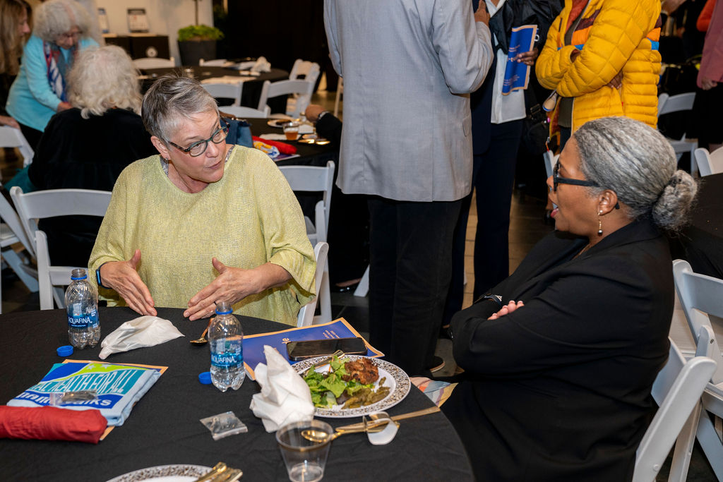 Two women sitting at a table with plates of food.
