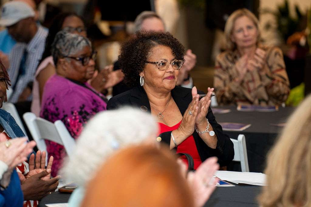 A group of people sitting at tables clapping.