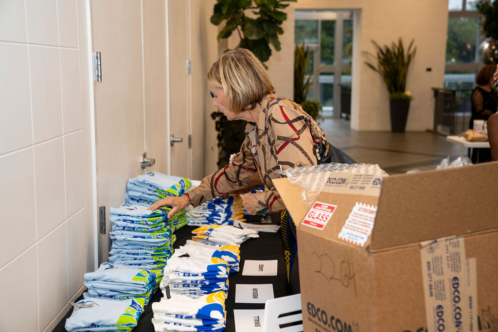 A woman in brown shirt standing next to boxes of diapers.