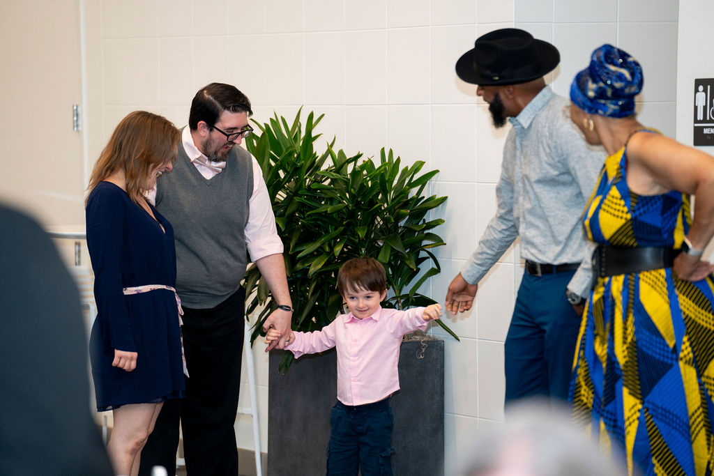 A young child holding hands with an adult.